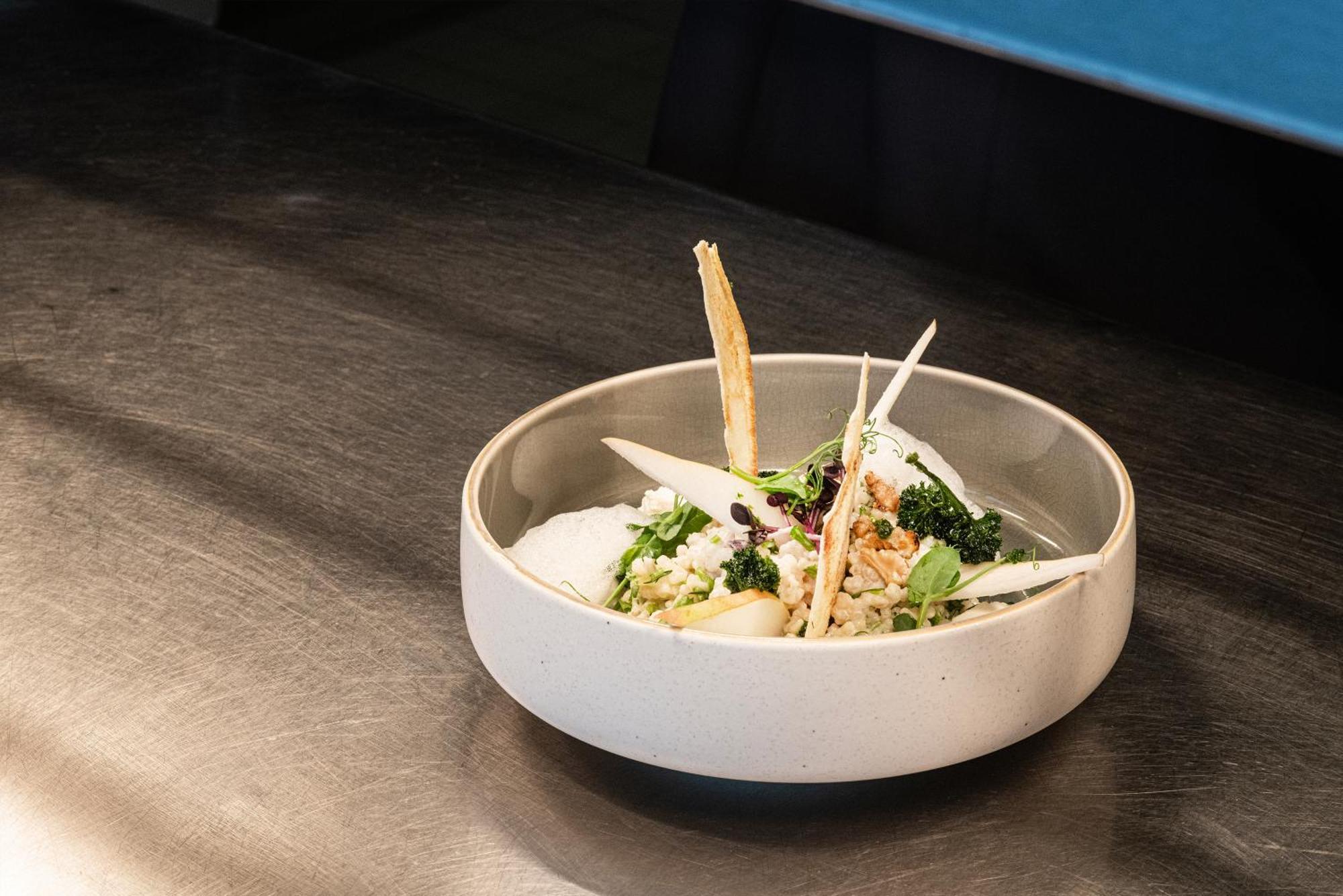 Frankfurt Airport Marriott Hotel Φραγκφούρτη Εξωτερικό φωτογραφία The photo shows a dish served in a modern, shallow bowl. The dish appears to contain a mix of ingredients, likely including grains or rice, topped with what seems to be fresh greens and garnishes. There are several thin, crispy pieces sticking out, p