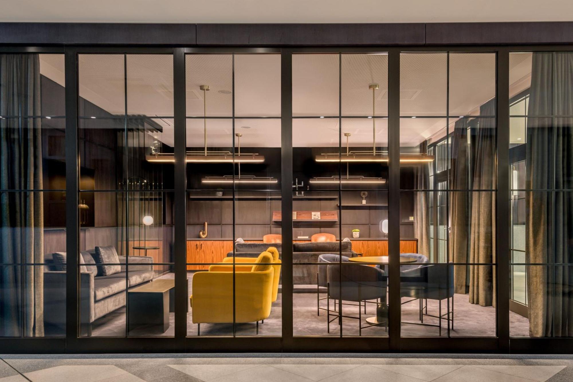 Frankfurt Airport Marriott Hotel Φραγκφούρτη Εξωτερικό φωτογραφία The photo showcases a modern, stylish interior that appears to be a lounge or meeting space. It features a large glass wall divided into panels, allowing a view of the inside. The interior is furnished with sleek, contemporary furniture, including a 
